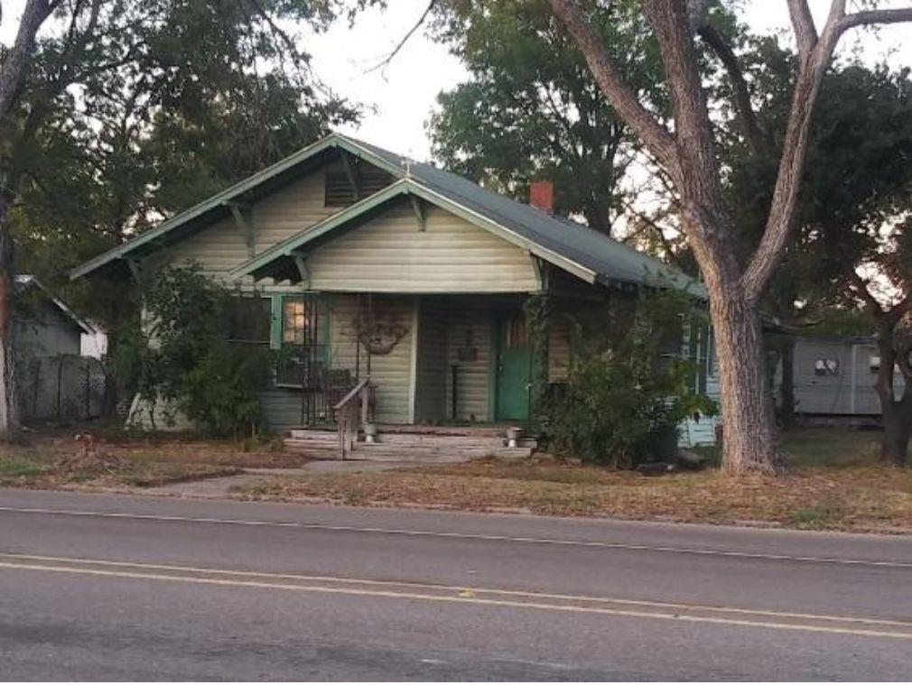 a front view of a house with garden and trees