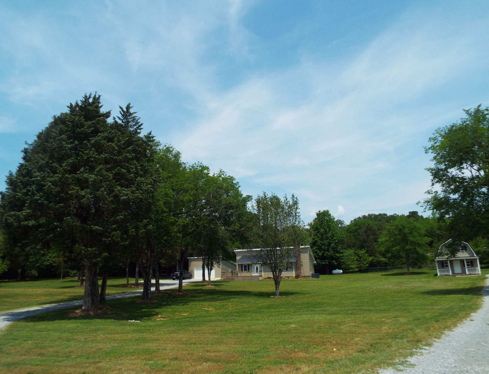 a view of grassy field with benches and trees all around