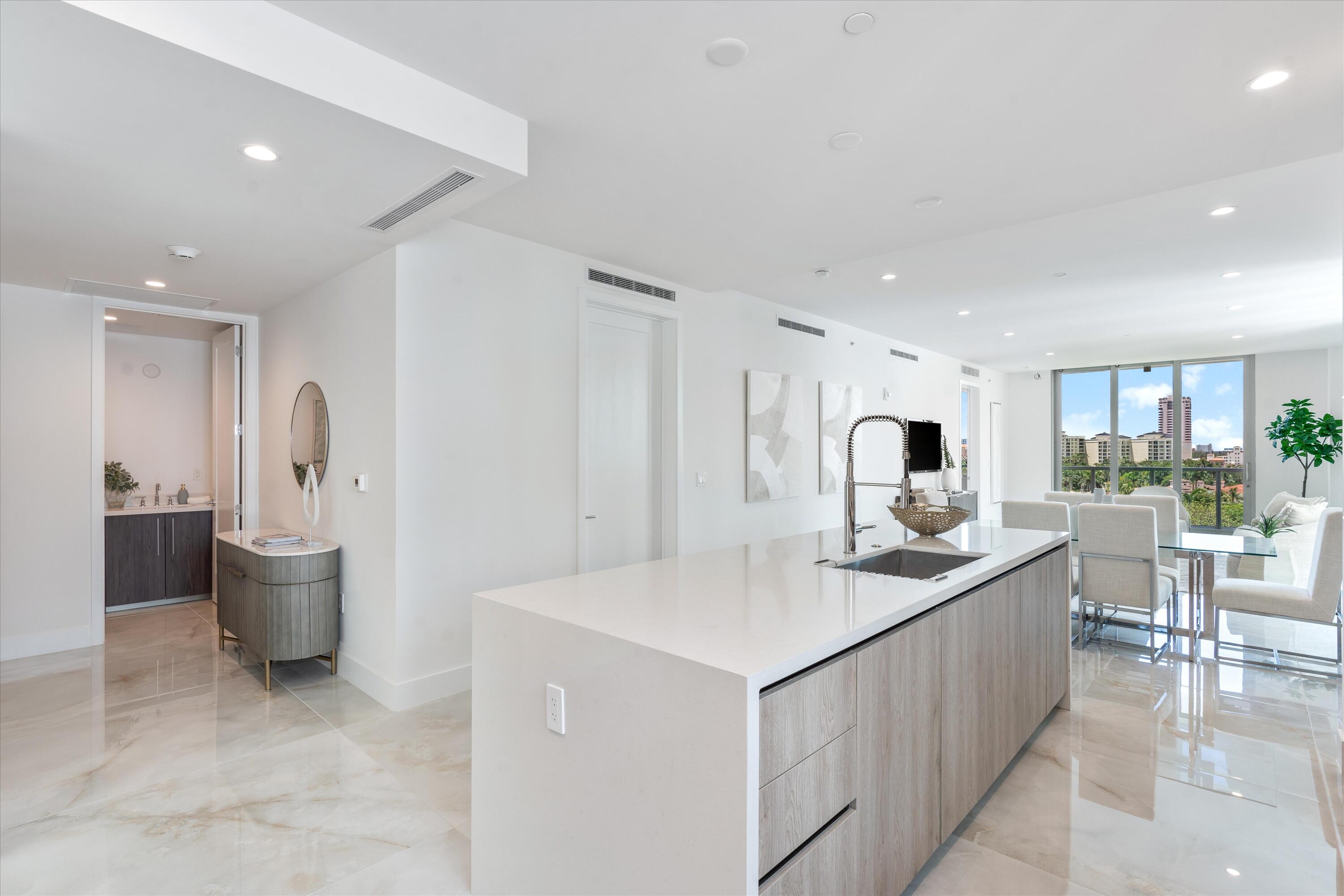 a large white kitchen with a sink stainless steel appliances and cabinets