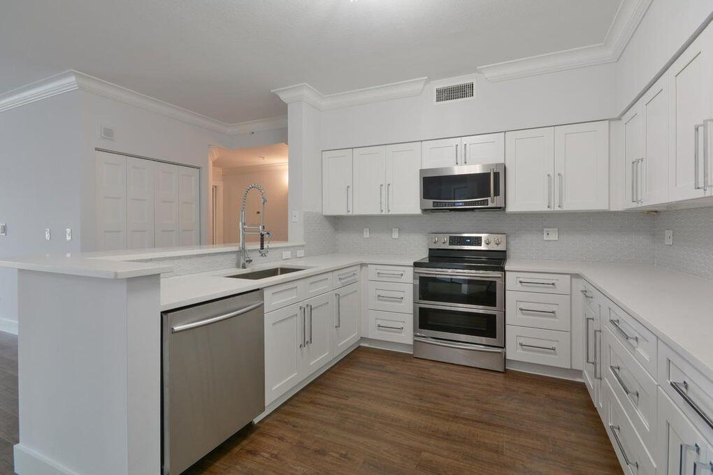 a kitchen with stainless steel appliances granite countertop a stove top oven a sink and white cabinets