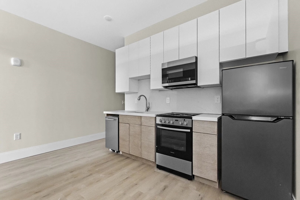 a kitchen with stainless steel appliances white cabinets and a stove top oven