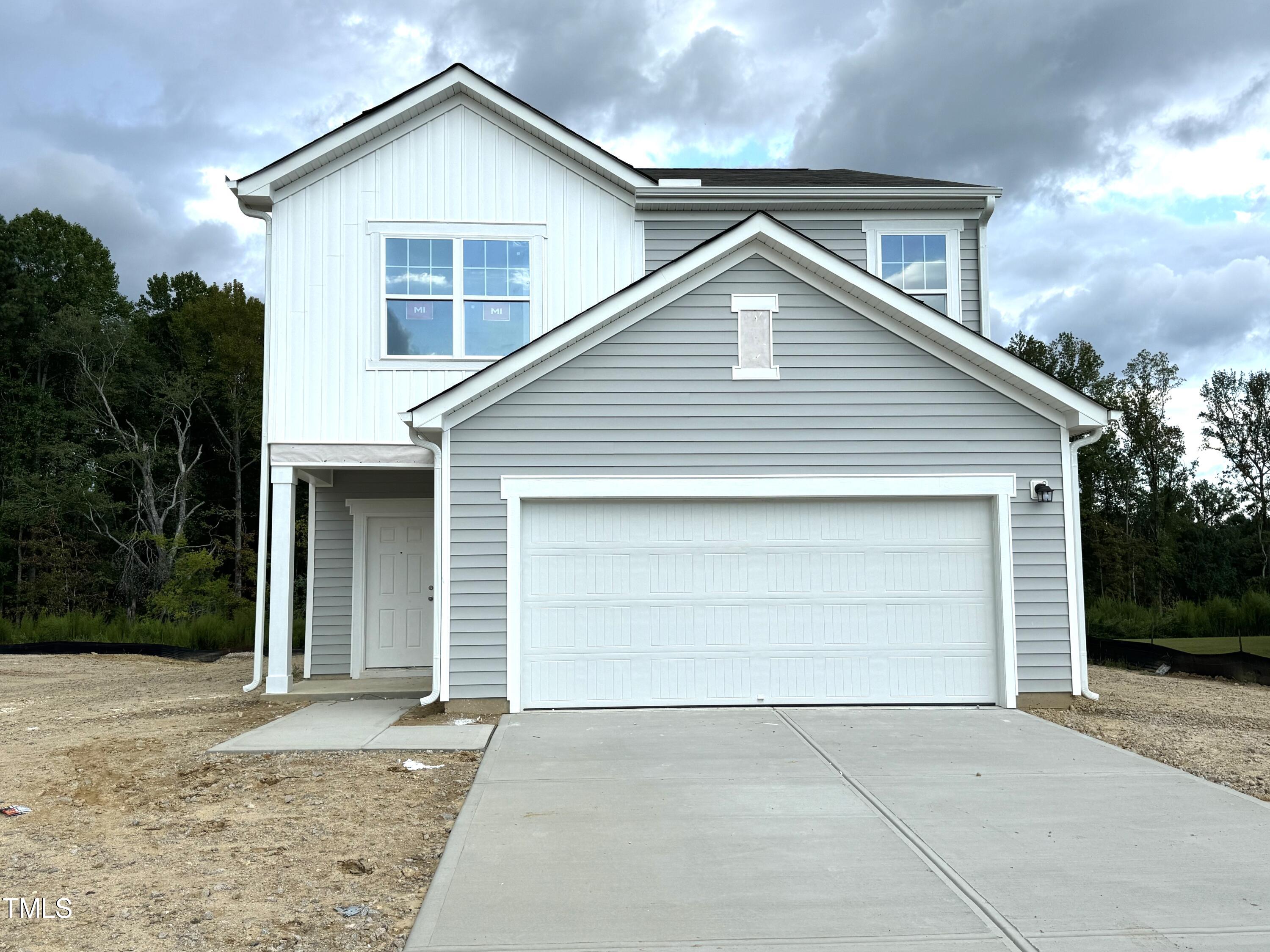 a front view of house with garage and trees