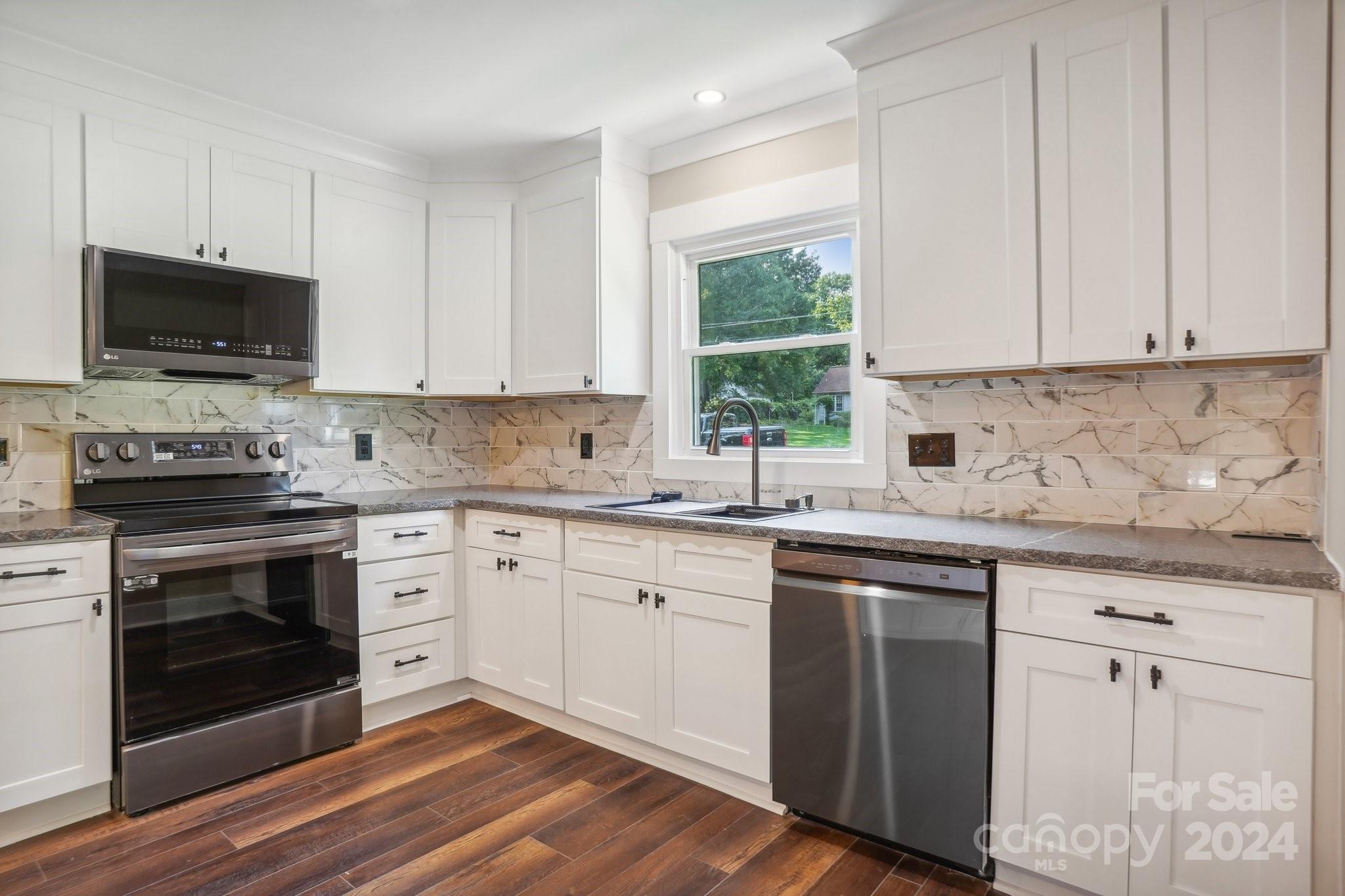 a kitchen with cabinets stainless steel appliances a sink and a window