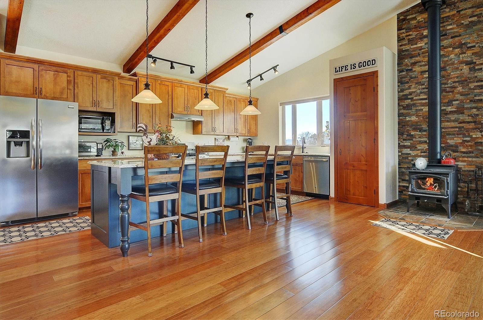 a dining room with stainless steel appliances wooden floor a large window and a rug