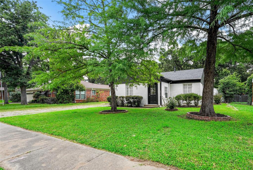 a view of a house with a yard and large trees