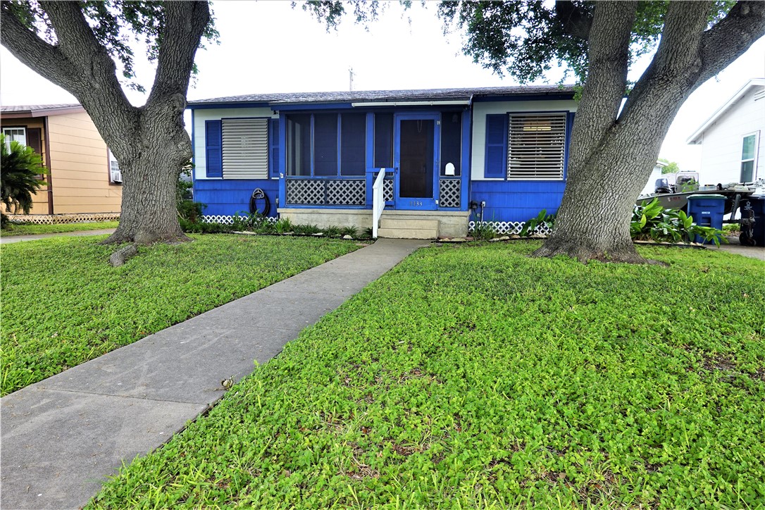 a view of a house with a yard and a large tree