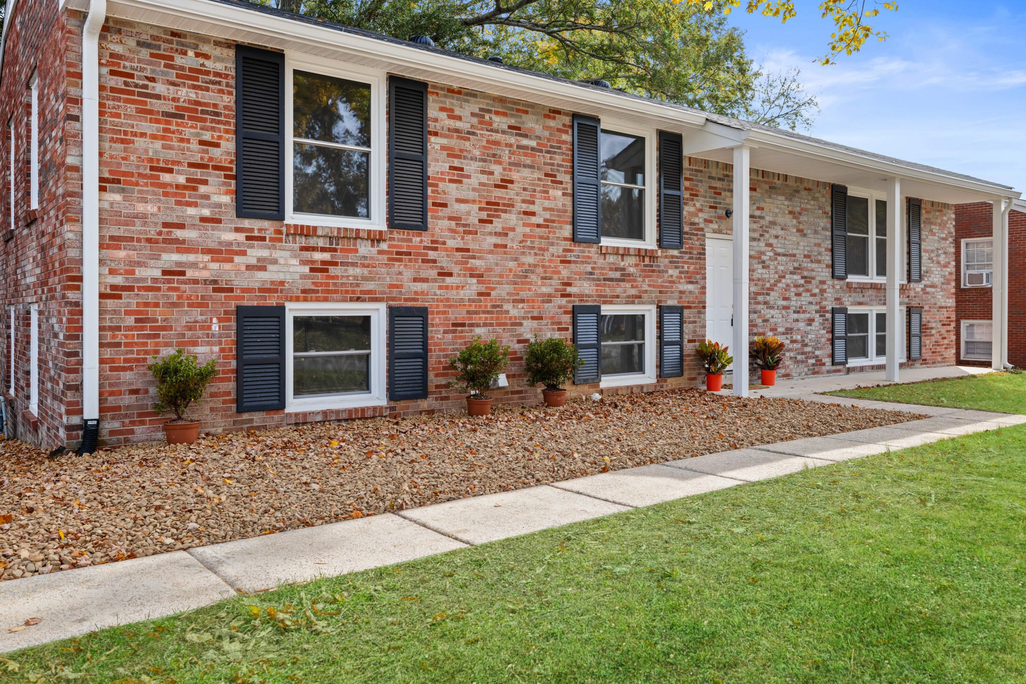 a view of a brick house with many windows plants and large tree