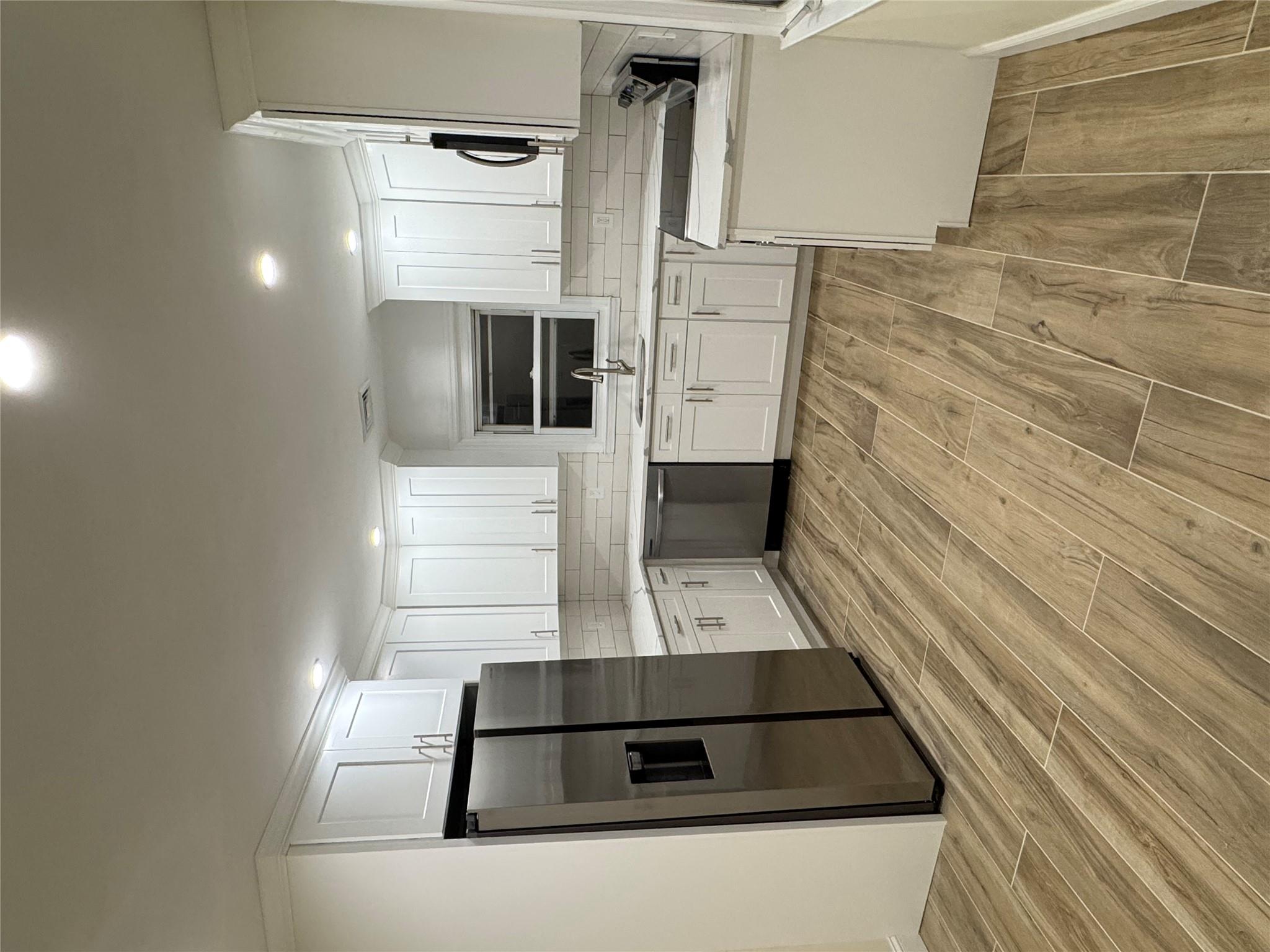 a kitchen with a refrigerator a stove top oven and white cabinets