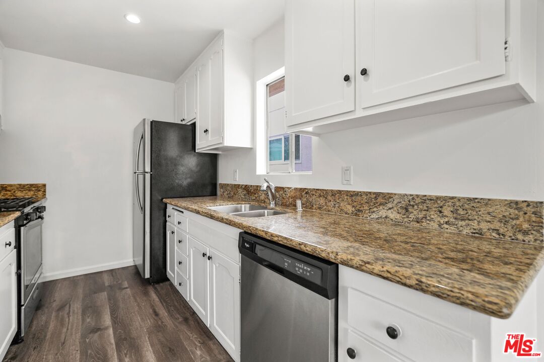 a kitchen with granite countertop cabinets stainless steel appliances and a counter space