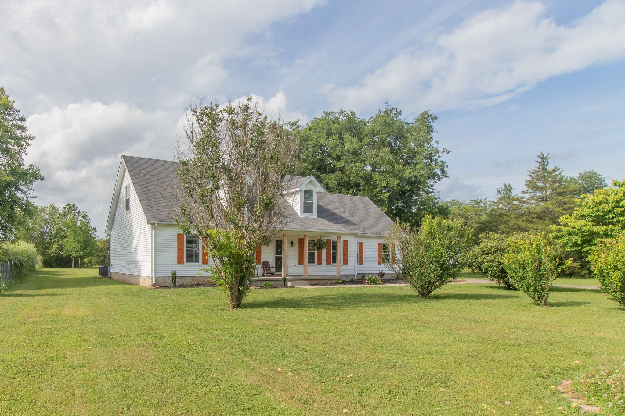 a front view of a house with a garden and tree