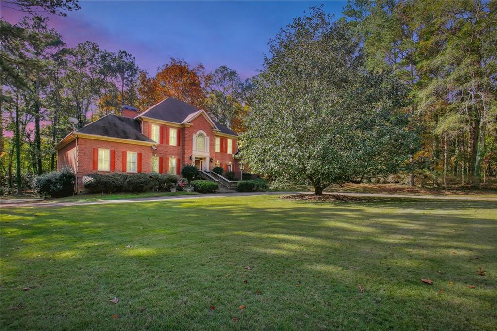 a front view of house with yard and trees in the background