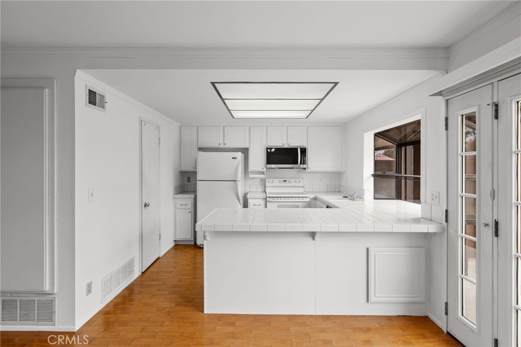 a large white kitchen with kitchen island a stove a sink and dishwasher with wooden floor