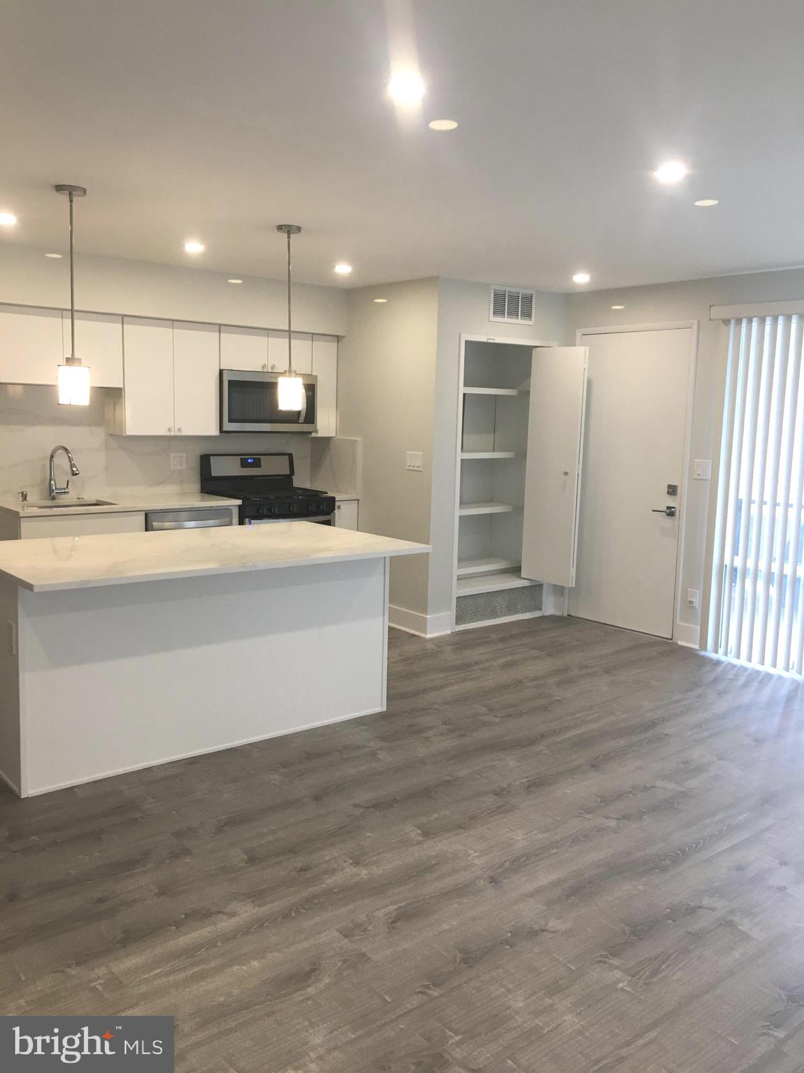 a large white kitchen with kitchen island a sink stainless steel appliances and cabinets