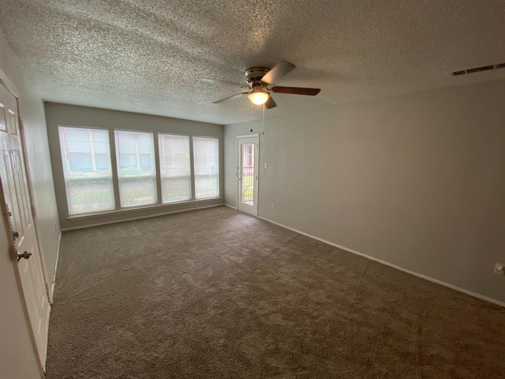 an empty room with chandelier fan and windows