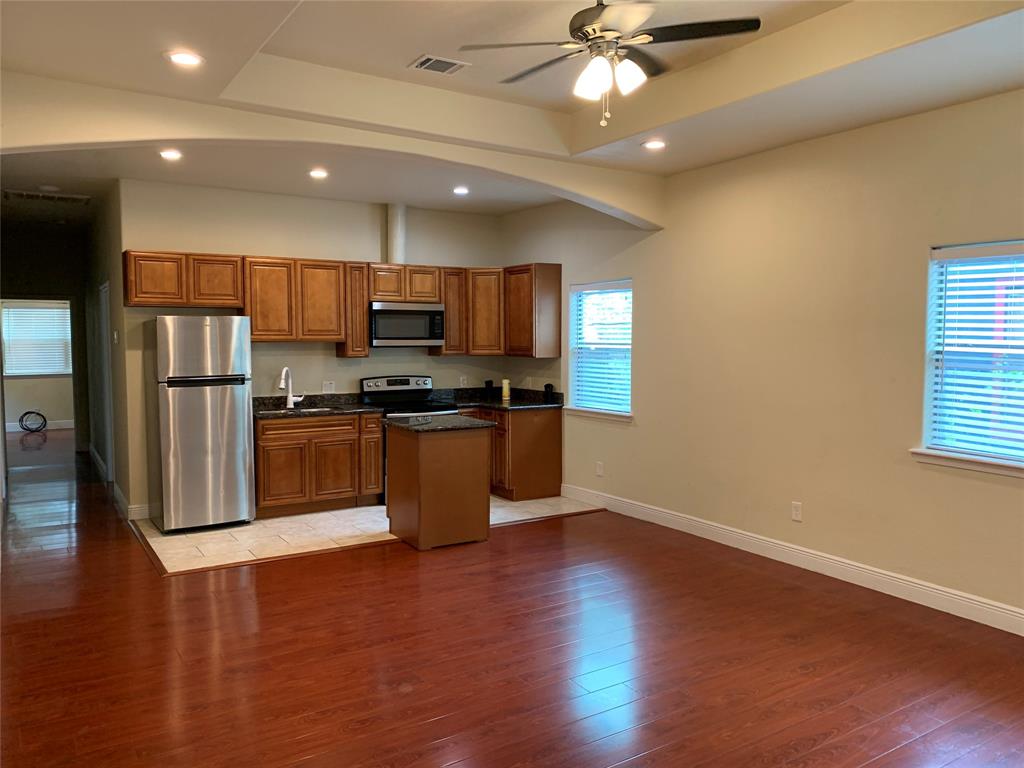 a kitchen with stainless steel appliances wooden floors and view living room