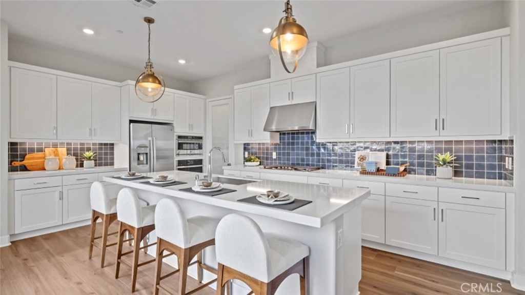 a kitchen with stainless steel appliances granite countertop a sink a stove a refrigerator cabinets and chairs