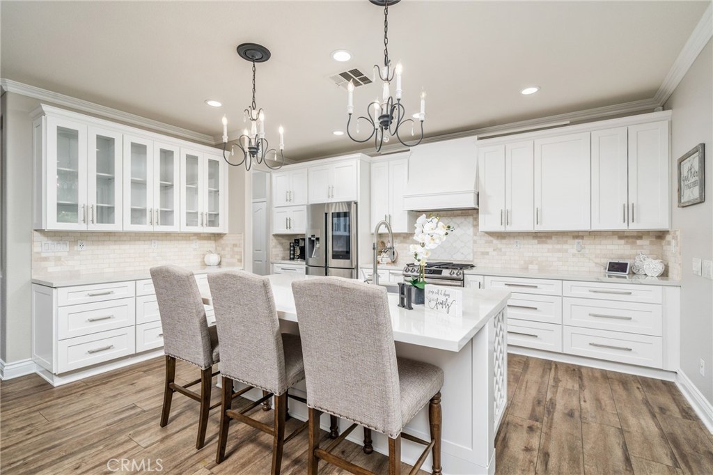 a kitchen with stainless steel appliances granite countertop a dining table chairs stove and white cabinets