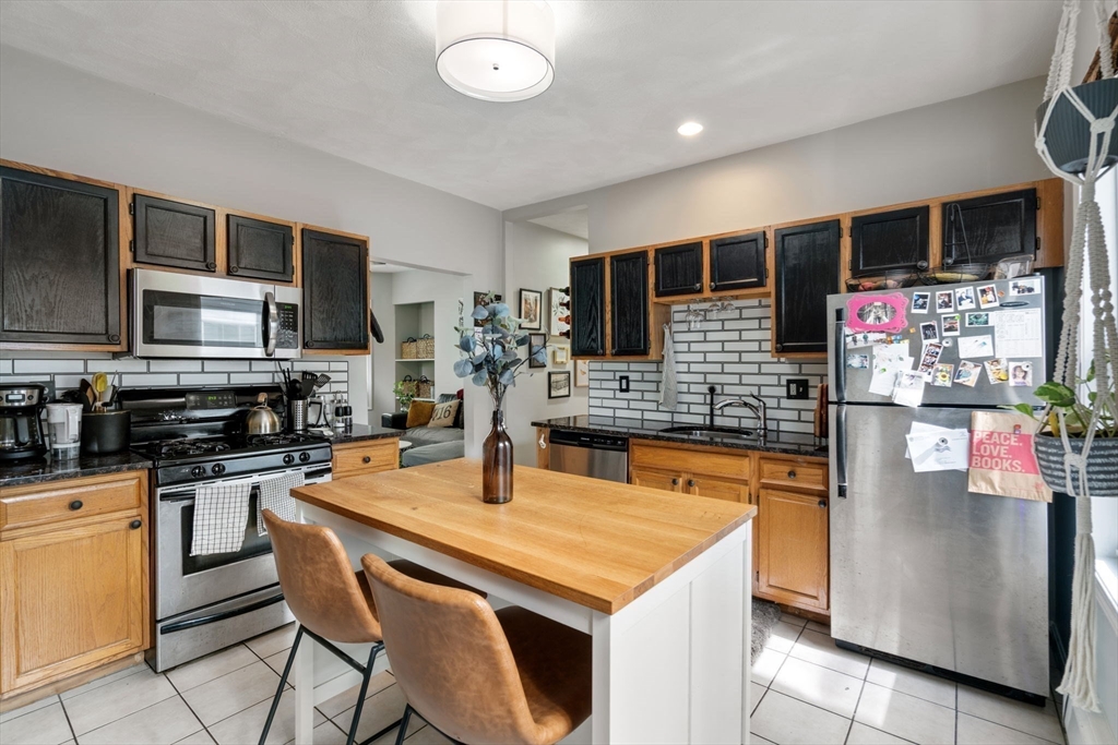 a kitchen with stainless steel appliances kitchen island granite countertop a sink dishwasher and a microwave with wooden cabinets