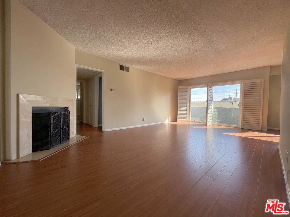 a view of an empty room with glass door and wooden floor