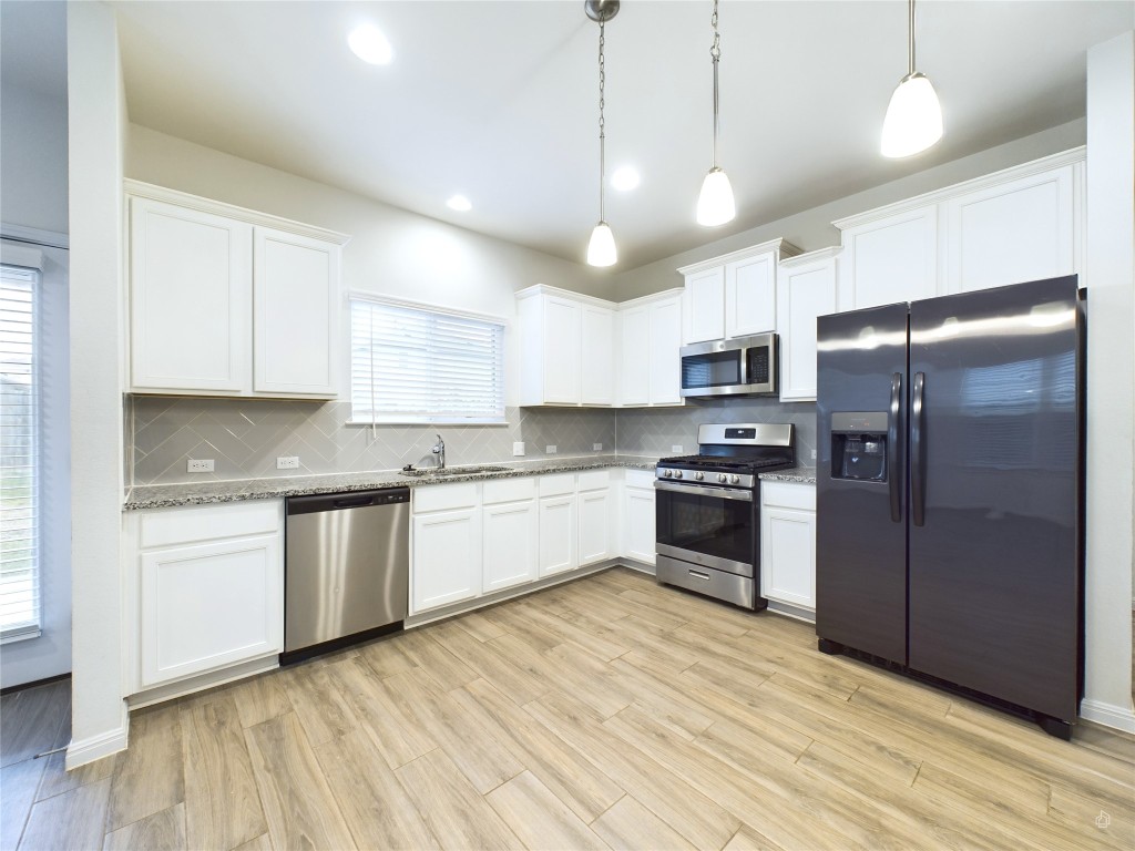 a large kitchen with cabinets wooden floor and stainless steel appliances