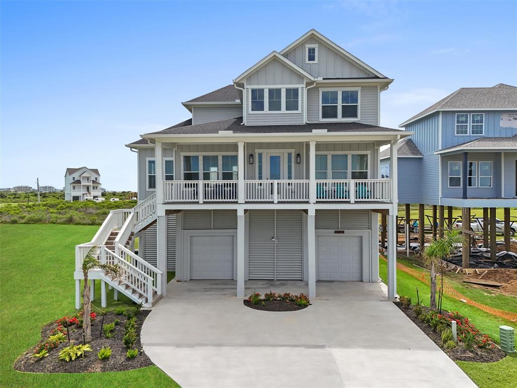 Discover the serene beauty of this elevated coastal home in Pointe West, featuring a spacious front porch perfect for enjoying panoramic green field views and the distant ocean breeze.