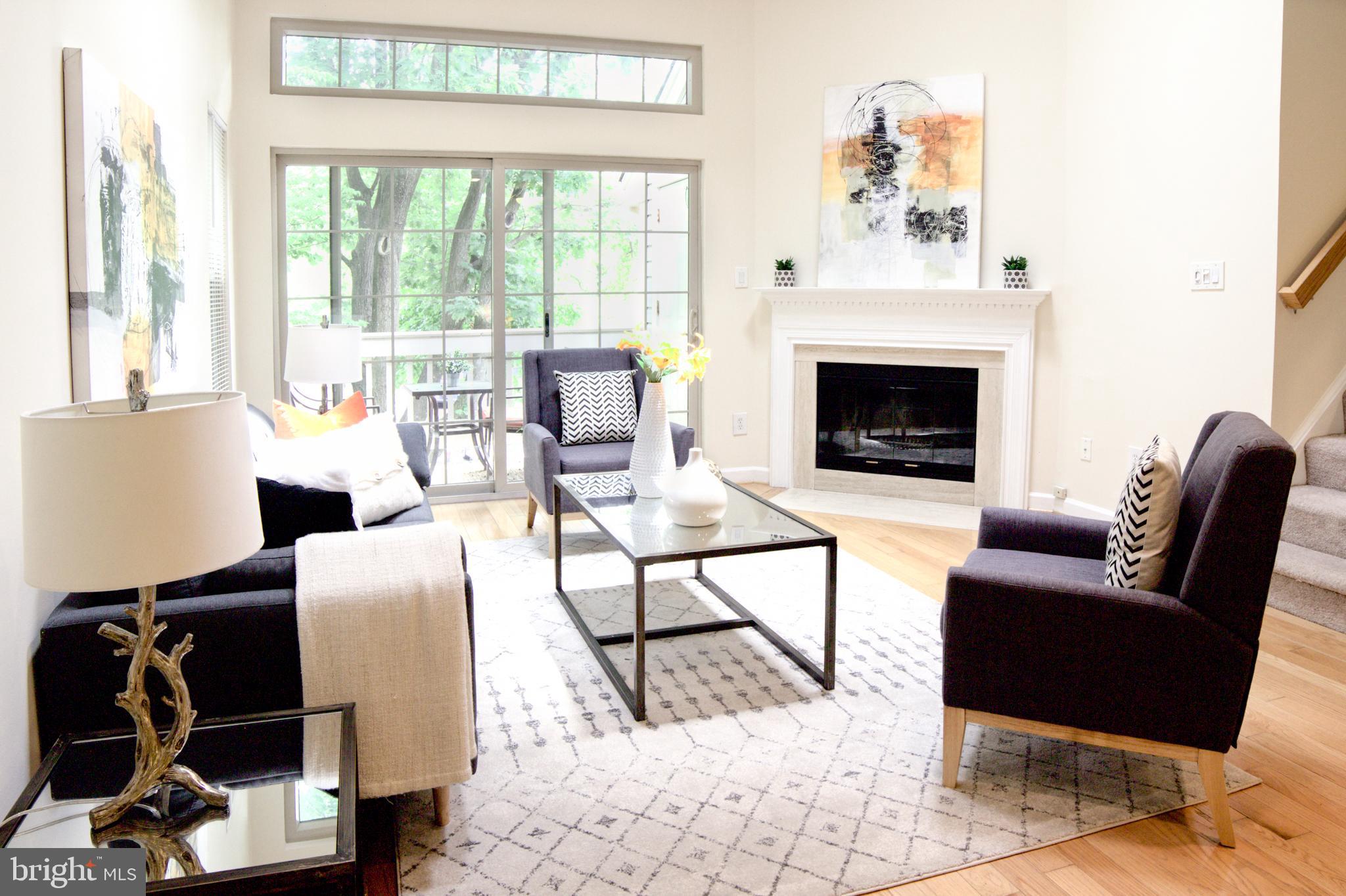 a living room with furniture a fireplace and a floor to ceiling window