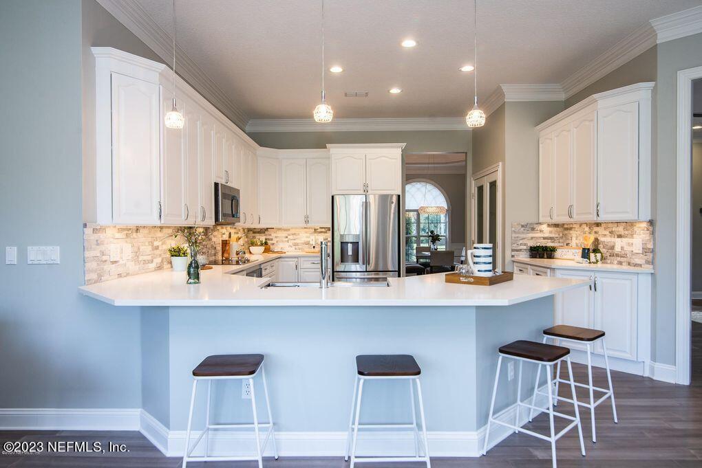 a kitchen with white cabinets and chairs