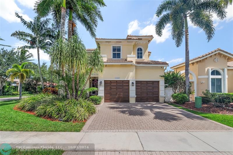 a front view of a house with a yard and palm trees