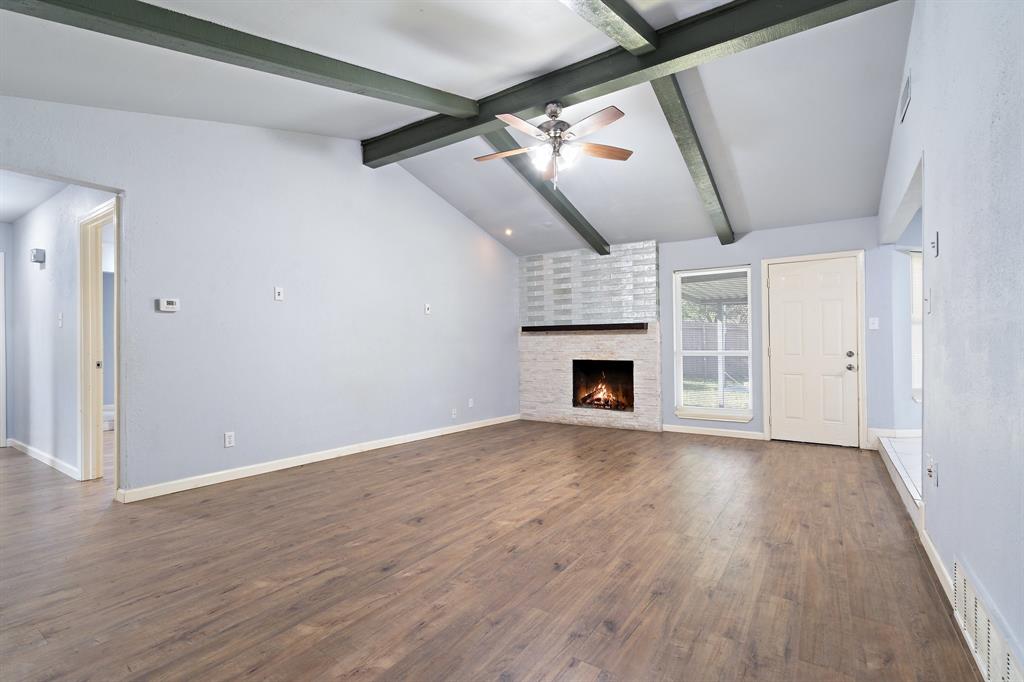 a view of empty room with wooden floor and fireplace