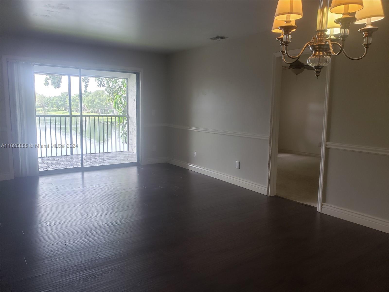 an empty room with wooden floor and windows with curtains