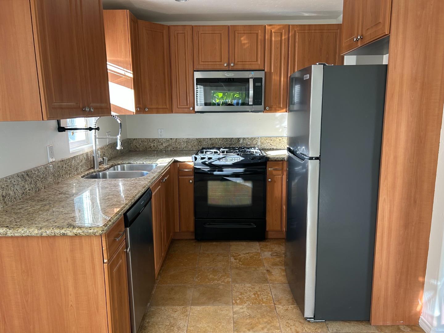 a kitchen with stainless steel appliances granite countertop a refrigerator and a stove top oven