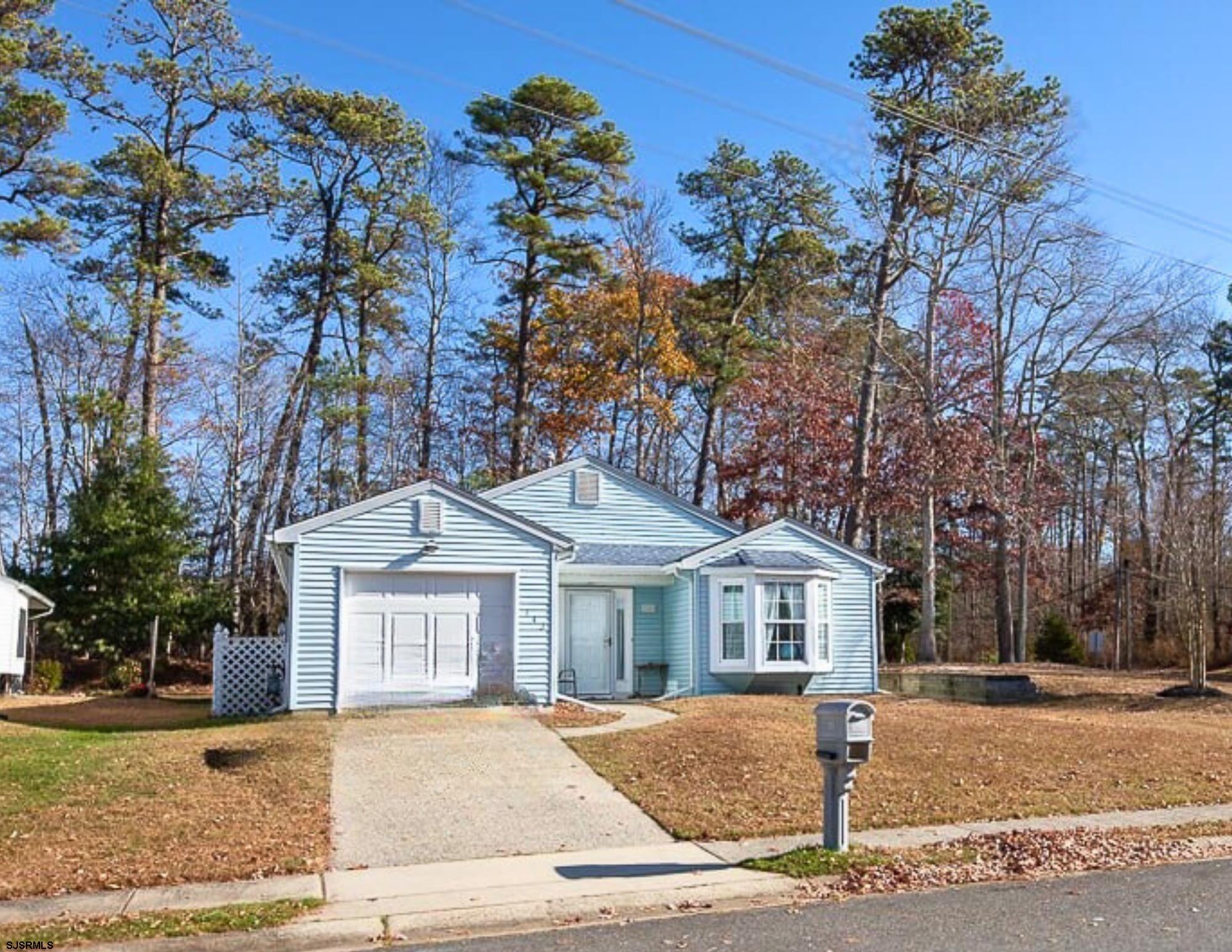 a front view of a house with a garden and trees