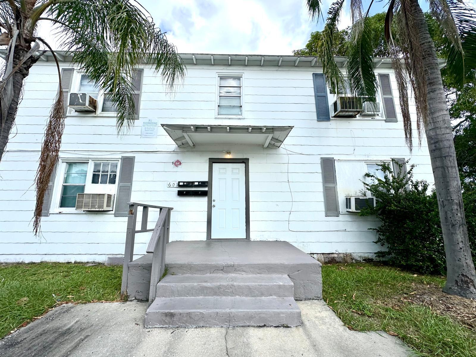 a front view of a house with a garden and palm trees