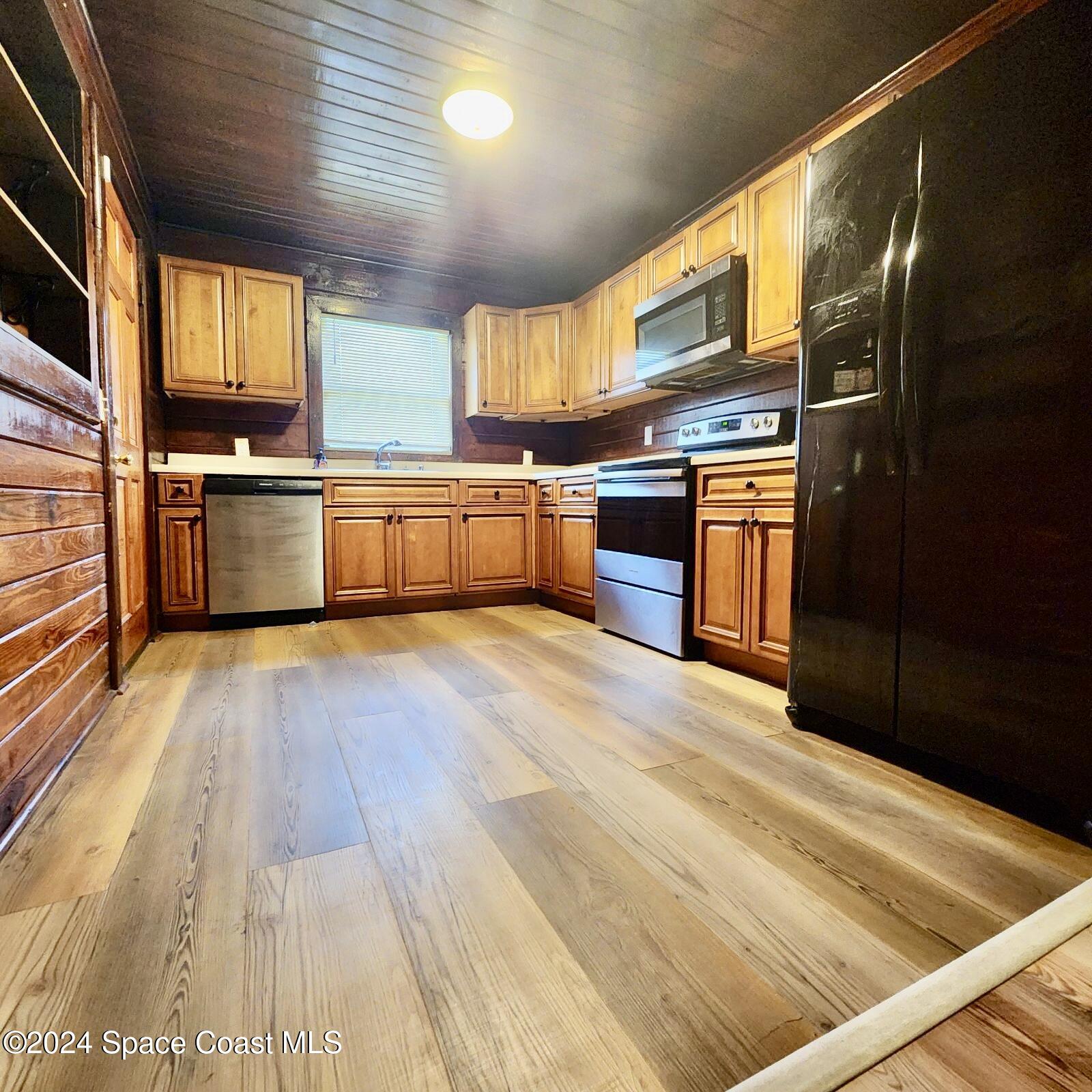 a large kitchen with stainless steel appliances wooden floors and wooden cabinets