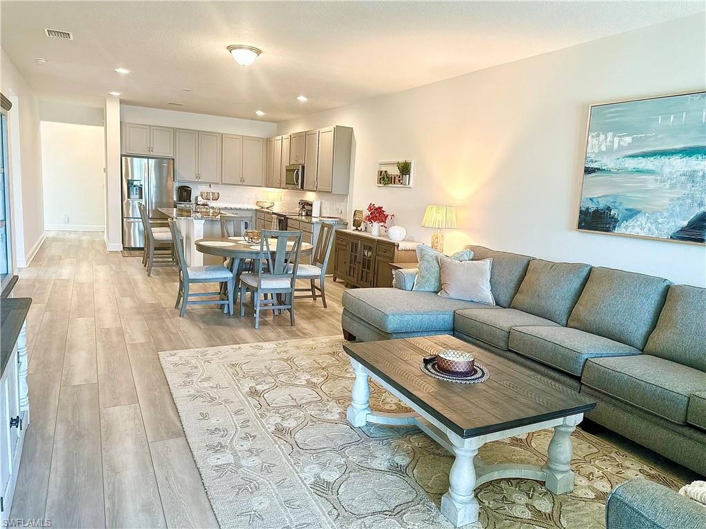 a living room with furniture and a dining table with kitchen view