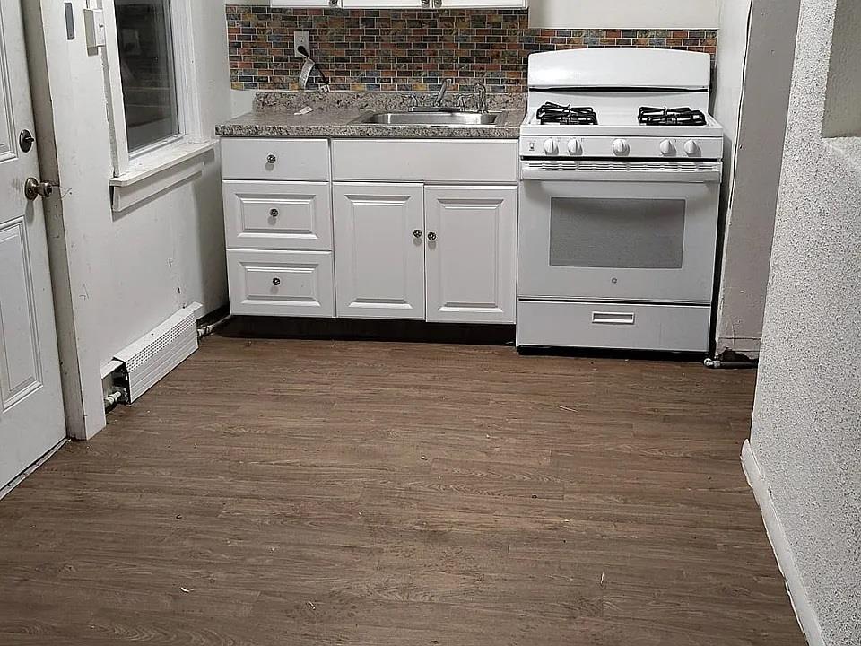 Kitchen with baseboard heating, dark hardwood / wood-style flooring, white cabinets, and white gas range oven