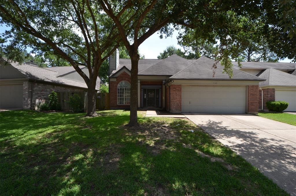 a brick house next to a yard with a large tree