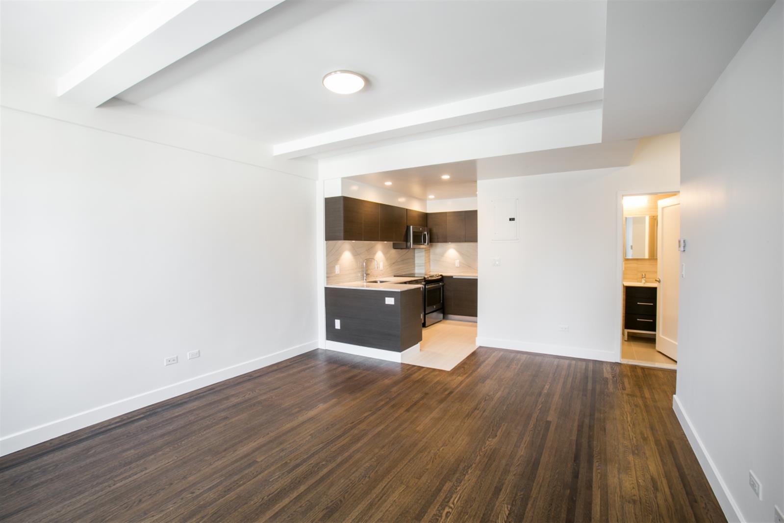 a view of a kitchen with a fridge and wooden floor