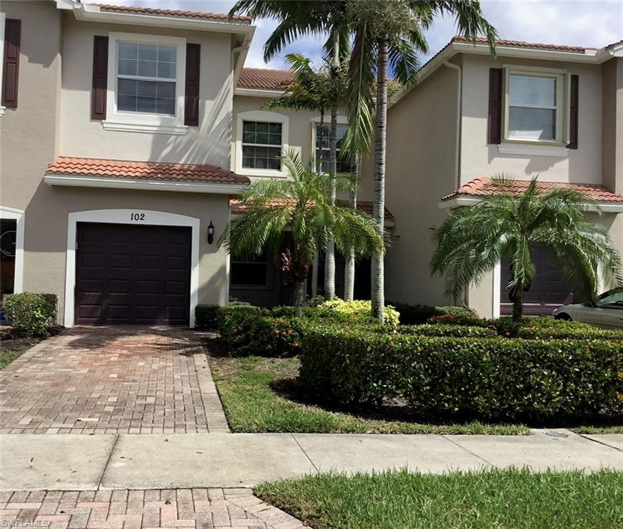 a front view of a house with a yard and palm trees