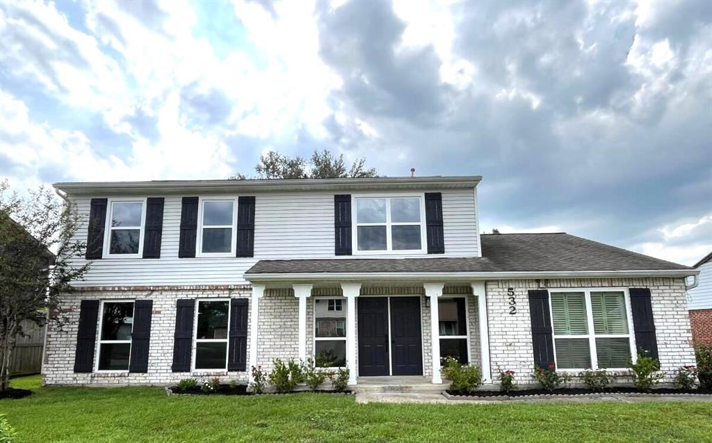 front view of a brick house with a yard