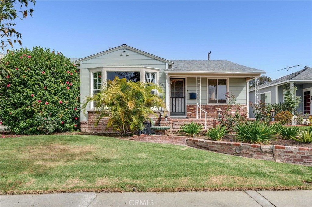 a front view of a house with a yard and potted plants