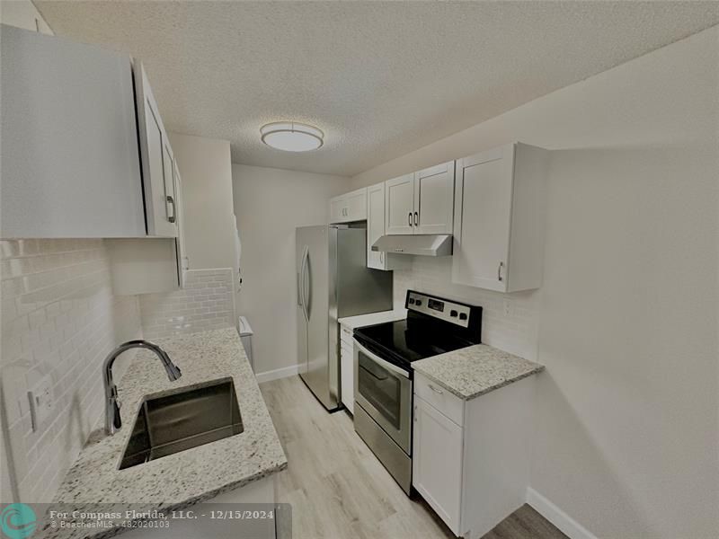 a kitchen with granite countertop a sink and a stove top oven