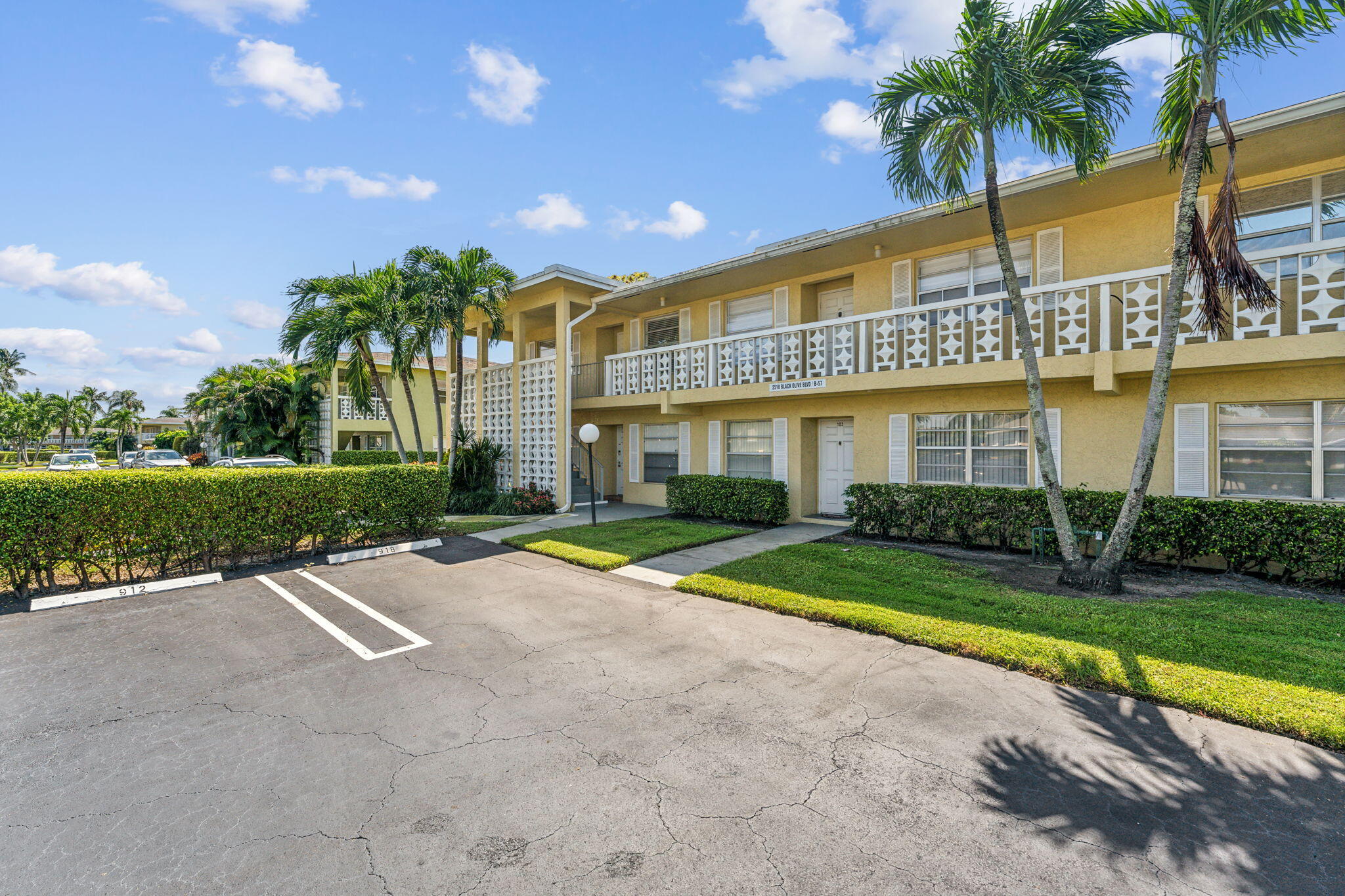 a view of a white building with a big yard and palm trees