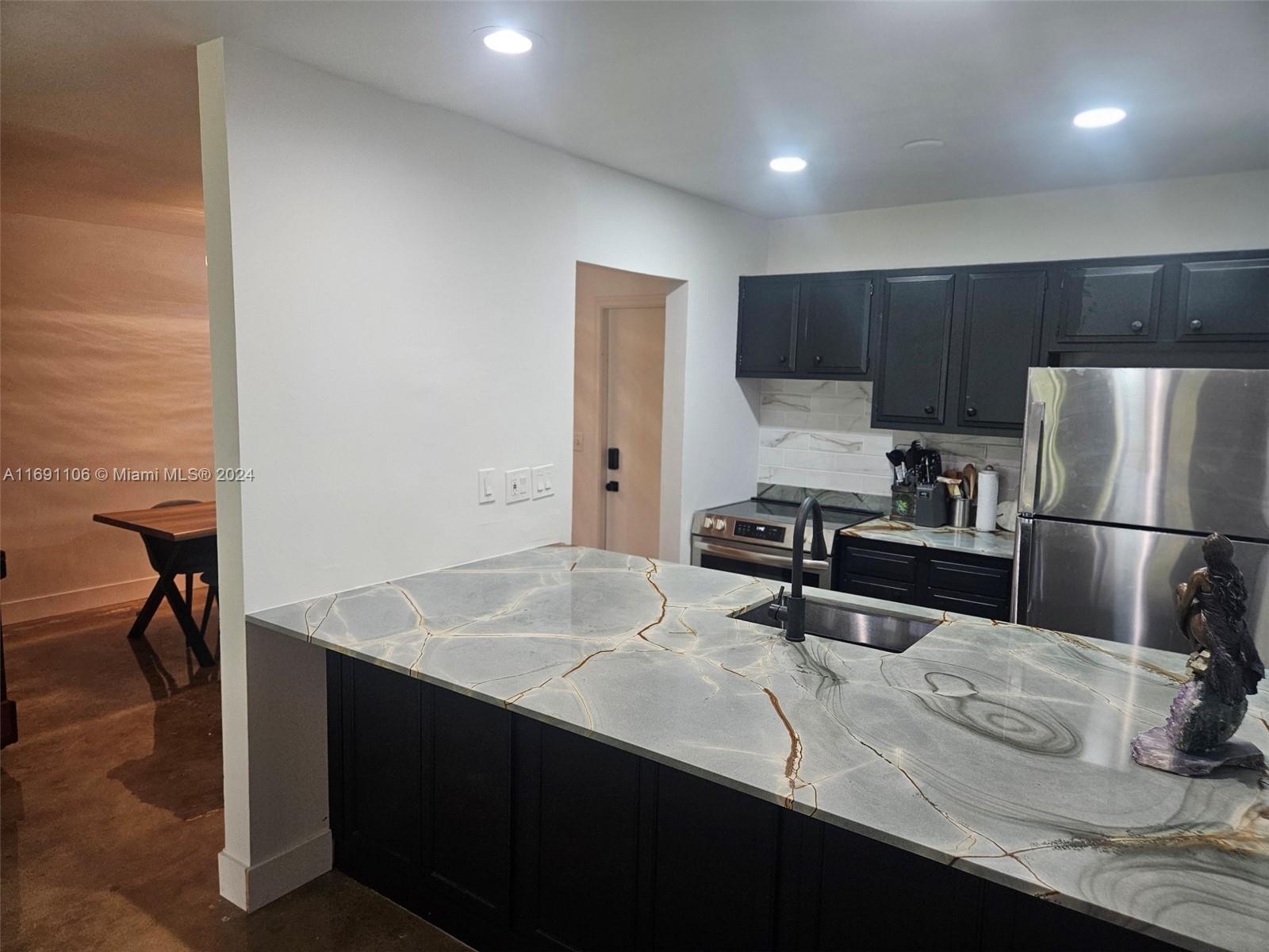 a kitchen with kitchen island a sink stainless steel appliances and refrigerator