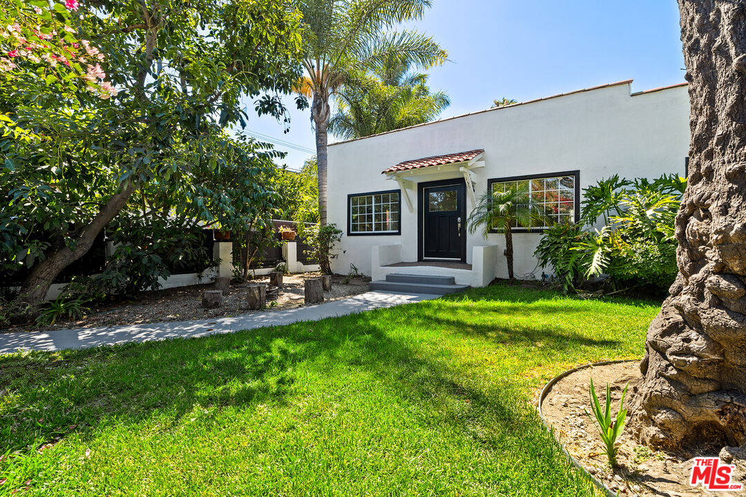 a backyard of a house with table and chairs potted plants and large tree