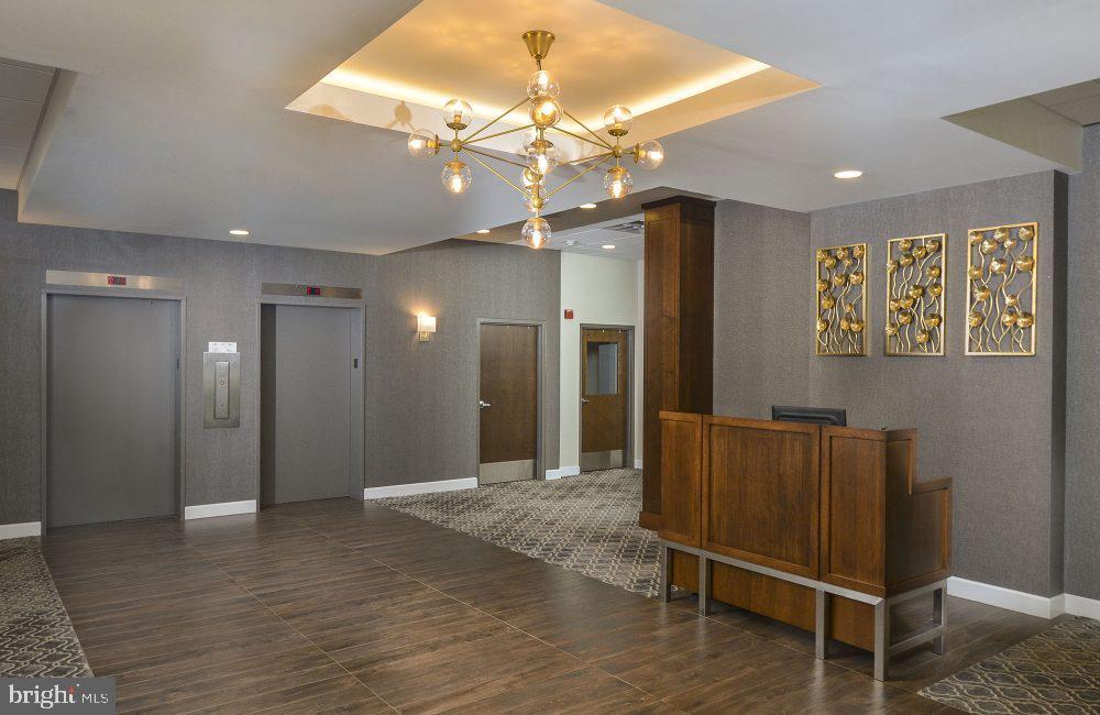 a view of a hallway with wooden floor and chandelier