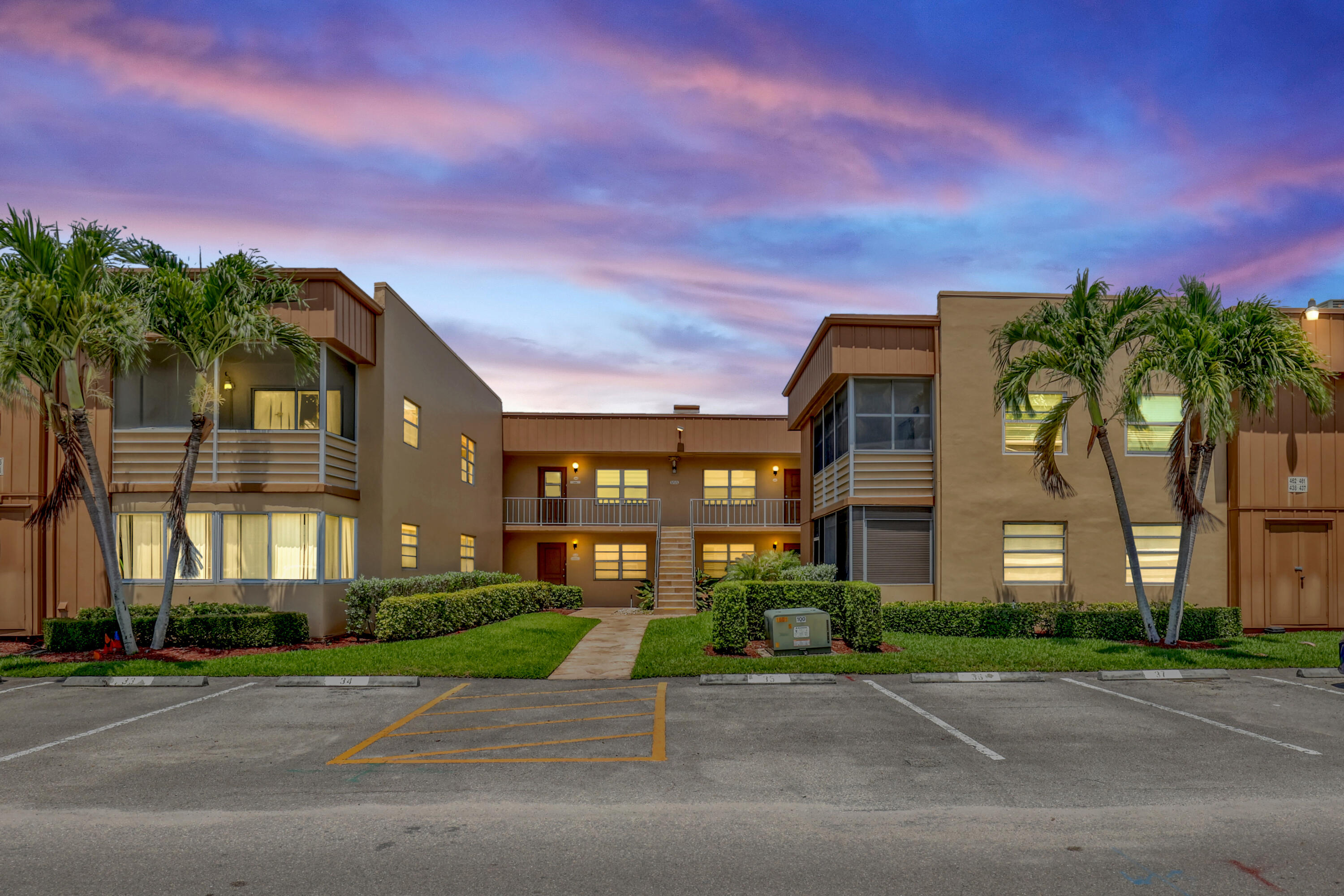 a front view of a multi story residential apartment building with yard and traffic signal