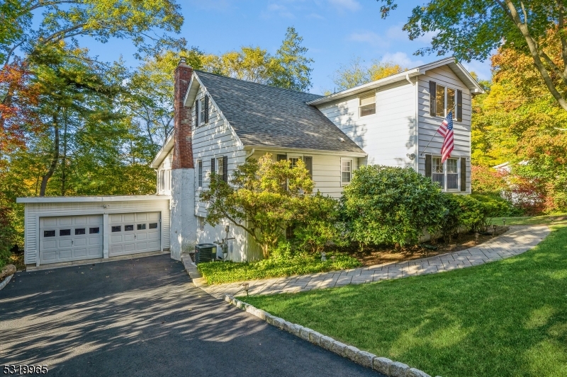 a view of a house with a small yard plants and large tree