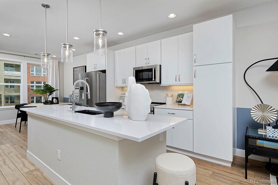 a kitchen with stainless steel appliances a sink a stove a refrigerator cabinets and chairs