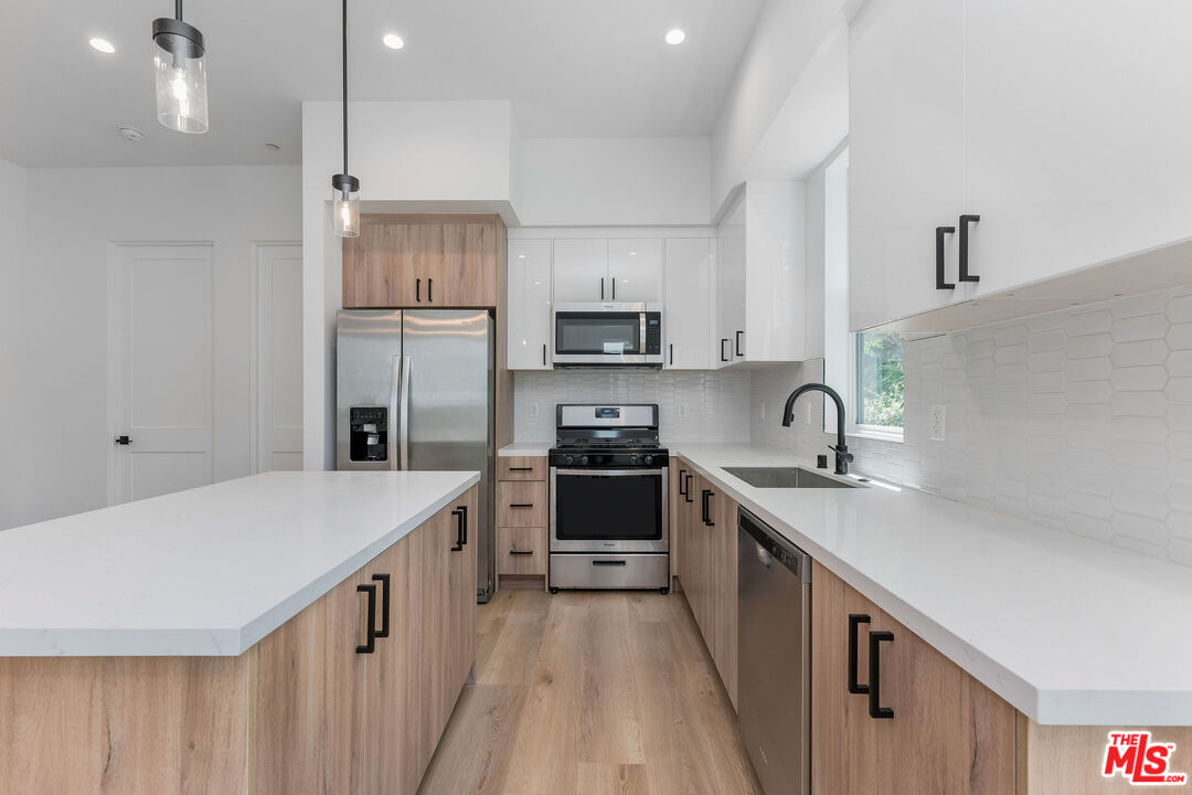 a kitchen with stainless steel appliances granite countertop a sink stove and refrigerator